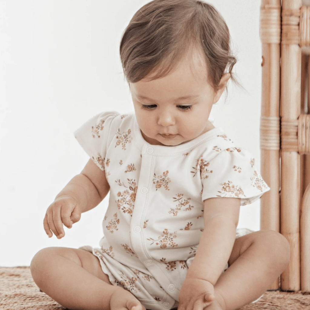 Child-Playing-with-Toes-Wearing-Aster-and-Oak-Organic-Posy-Floral-Ruffle-Romper-Naked-Baby-Eco-Boutique
