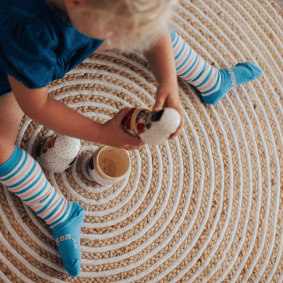 A little girl sitting on a rug with blue Lamington Merino Wool socks that stay on.