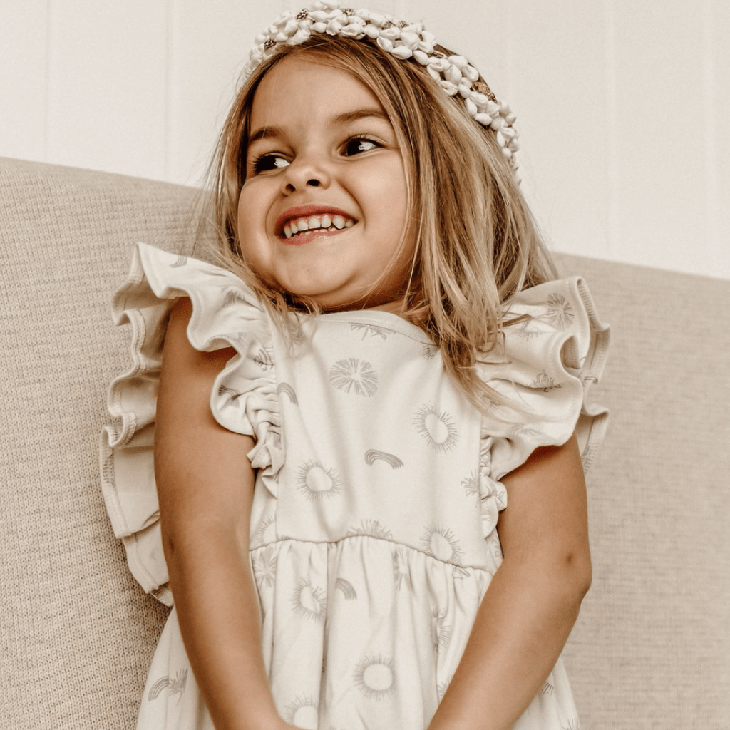 Close-up-of-Little-Girl-Smiling-Wearing-Aster-and-Oak-Sunny-Daze-Ruffle-Dress-Naked-Baby-Eco-Boutique