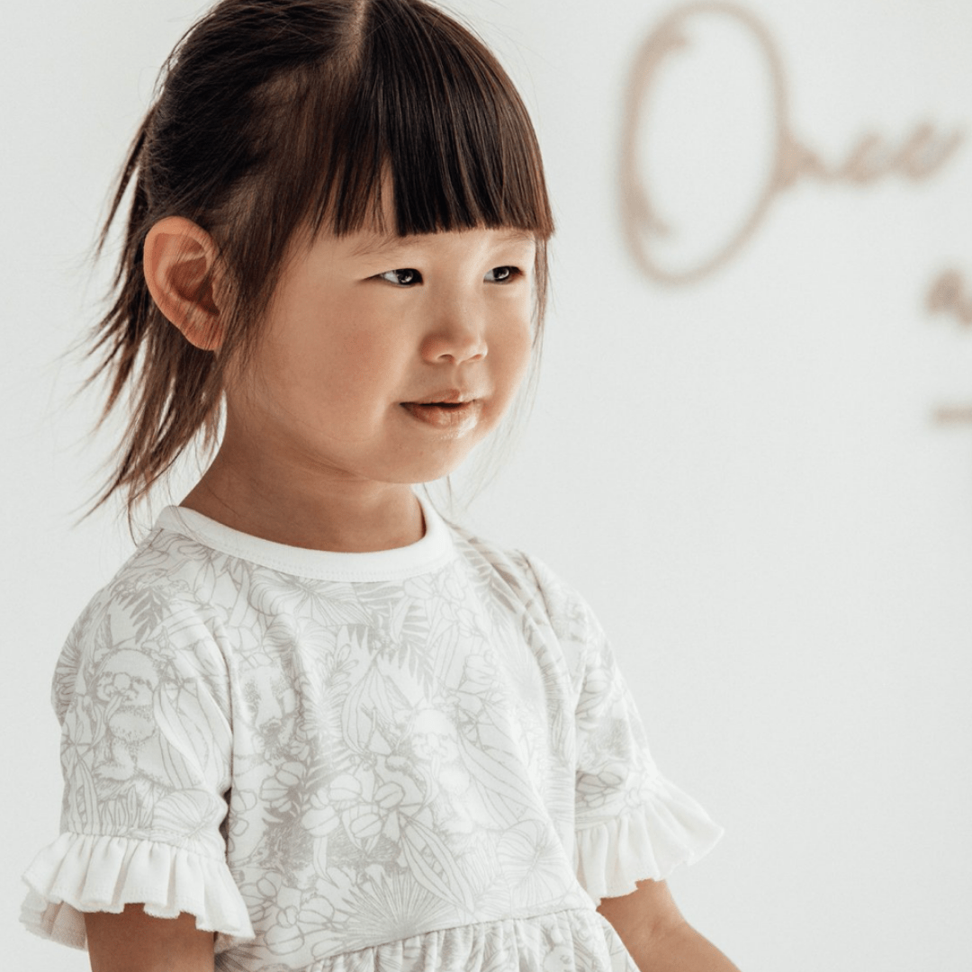 A little girl wearing the Aster & Oak Organic Animal Frill Skater Dress - LUCKY LAST - 2 YEARS.