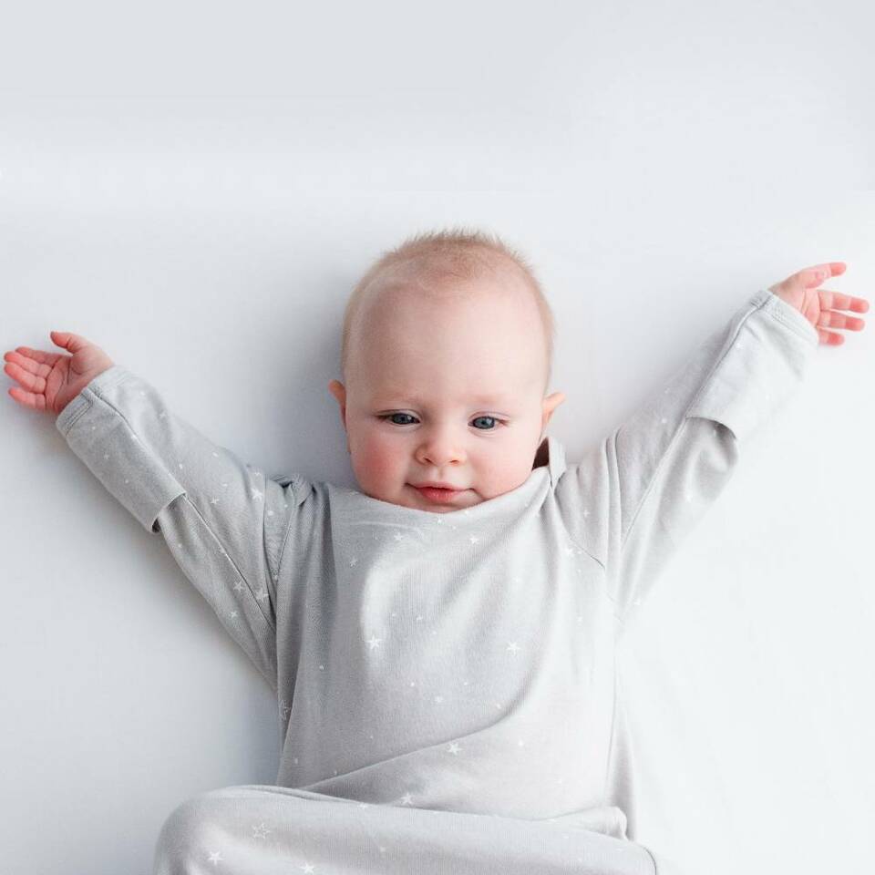 Cute-Baby-with-Arms-up-Wearing-Woolbabe-Merino-and-Organic-Cotton-Sleeping-Gown-Pebble-Stars-Naked-Baby-Eco-Boutique