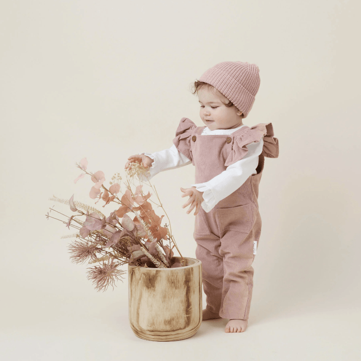 Cute-Toddler-Standing-Looking-at-Flowers-Wearing-Aster-and-Oak-Organic-Cotton-Pom-Pom-Beanie-Rose-Naked-Baby-Eco-Boutique