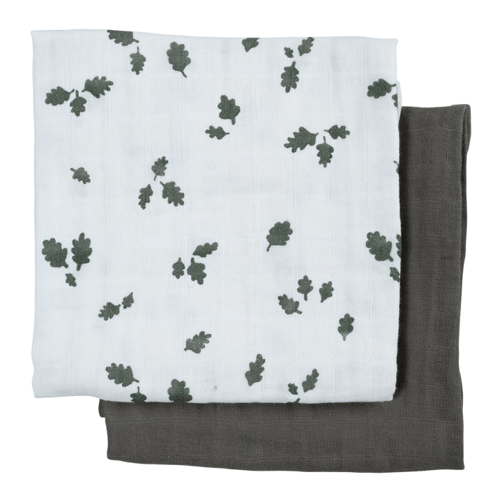 An organic Fabelab muslin swaddle blanket with green leaves on it.