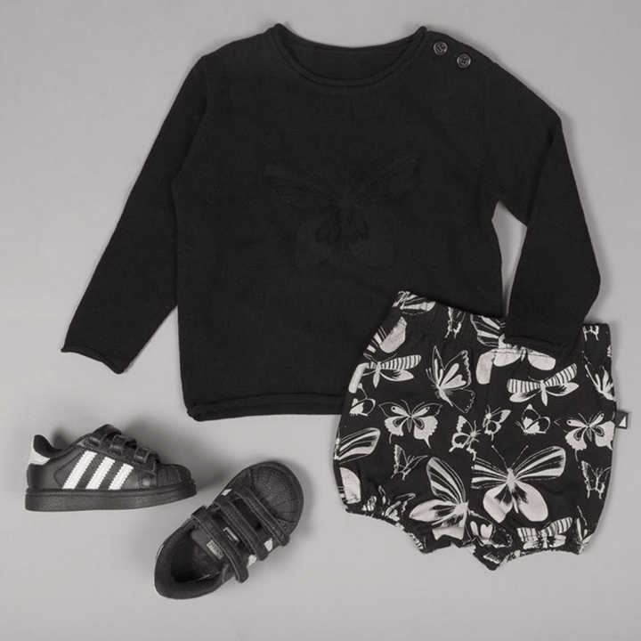 Children's outfit with an Anarkid Knit Wool Sweater featuring a butterfly design, matching shorts with a butterfly pattern, and a pair of black sneakers.