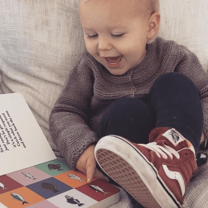 Happy-Boy-Looking-At-Pages-In-Fish-Of-Aotearoa-Board-Book-Naked-Baby-Eco-Boutique