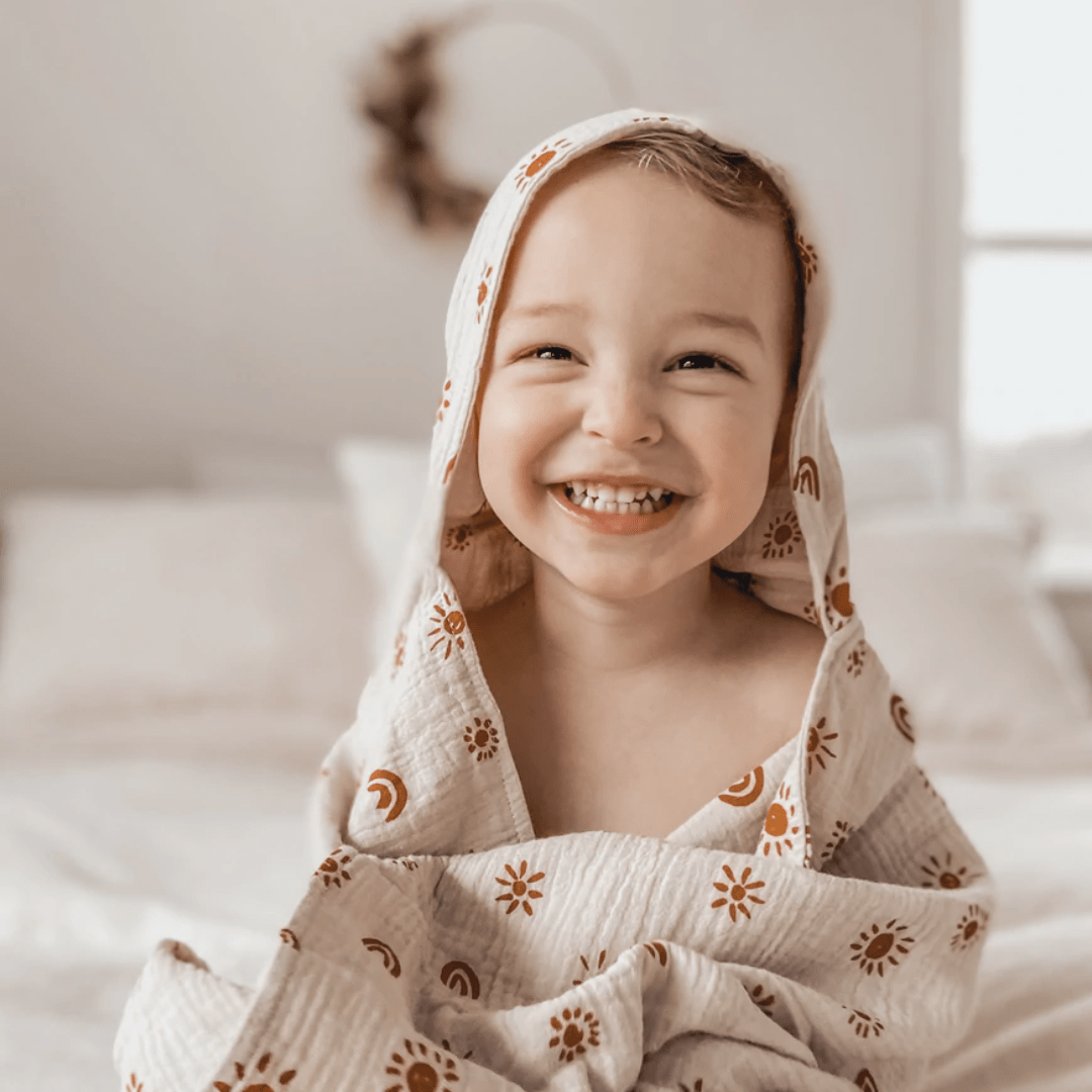 Happy-Boy-Wearing-Over-The-Dandelions-Organic-Muslin-Hooded-Towel-Sand-Amber-Naked-Baby-Eco-Boutique