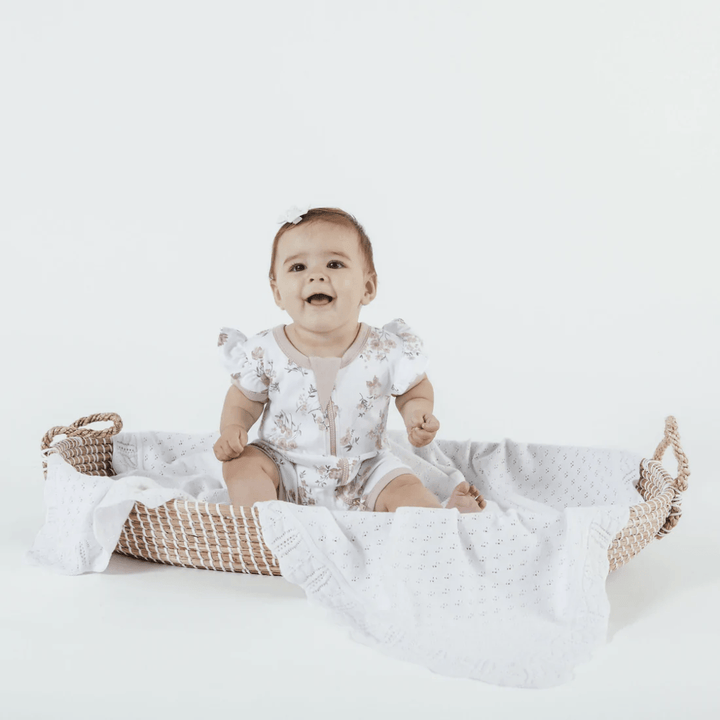 Happy-Girl-Sitting-Wearing-Aster-And-Oak-Organic-Cotton-Flutter-Sleeve-Zip-Romper-Primrose-Naked-Baby-Eco-Boutique