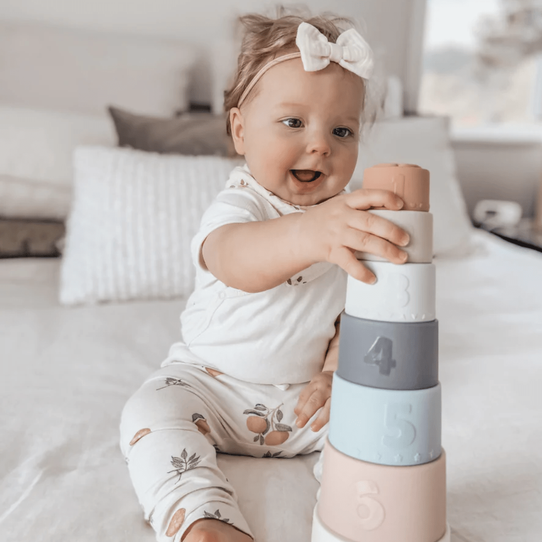 Happy-Girl-Stacking-Over-The-Dandelions-Stacking-Cups-Stacked-Naked-Baby-Eco-Boutique