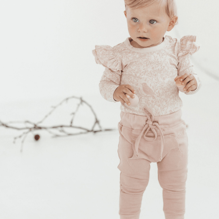 Happy-Girl-Wearing-Aster-And-Oak-Organic-Cotton-Jogger-Pants-Rose-Naked-Baby-Eco-Boutique