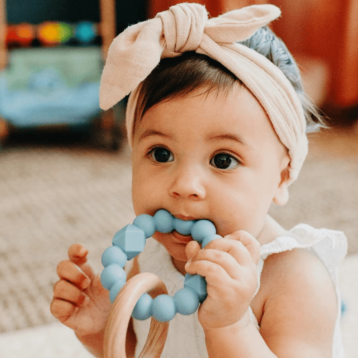 Jellystone-Designs-Wood-Silicone-Moon-Teether-Little-Girl-Using-Soft-Blue-Teether-Naked-Baby-Eco-Boutique