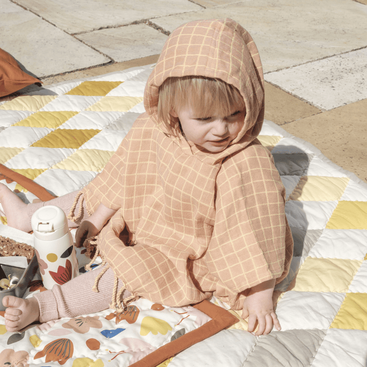 Little-Girl-Having-Snacks-Wearing-Fabelab-Organic-Cotton-Grid-Kids-Poncho-Naked-Baby-Eco-Boutique