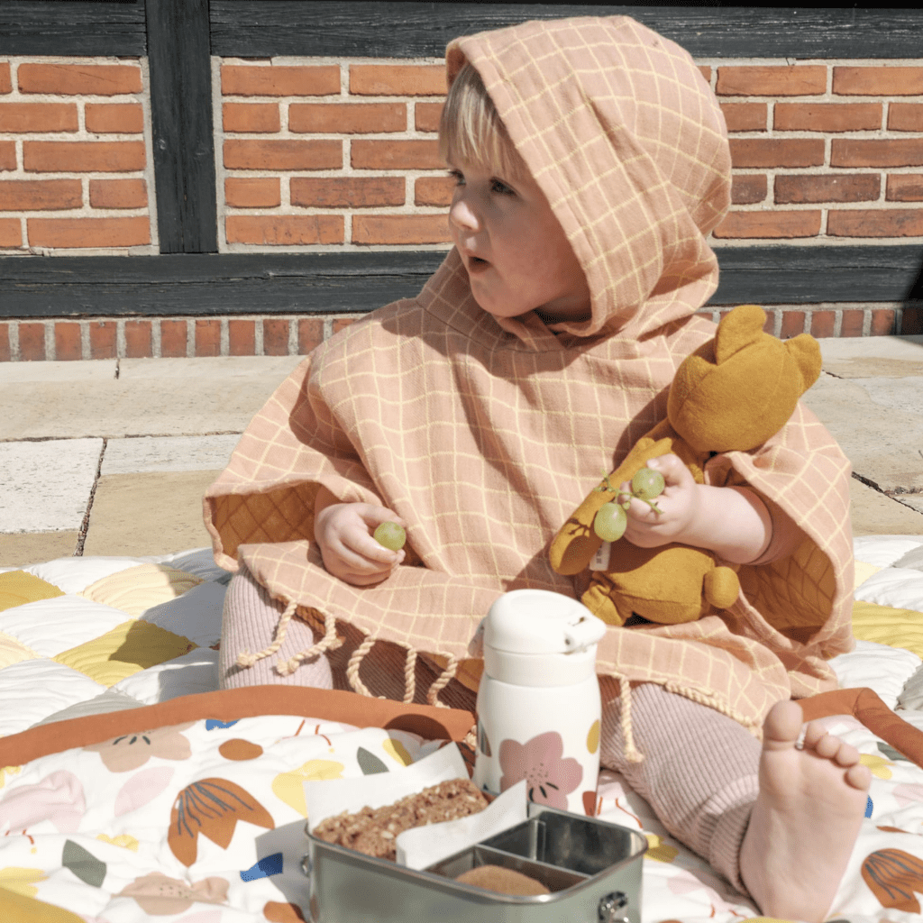 Little-Girl-Having-a-Picnic-Wearing-Fabelab-Organic-Cotton-Grid-Kids-Poncho-Old-Rose-Naked-Baby-Eco-Boutique