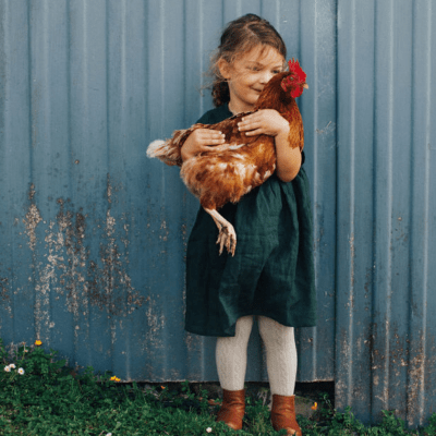 Little-Girl-Holding-Chicken-Wearing-Lamington-Merino-Baby-Kids-Cable-Tights-Oatmeal-Naked-Baby-Eco-Boutique