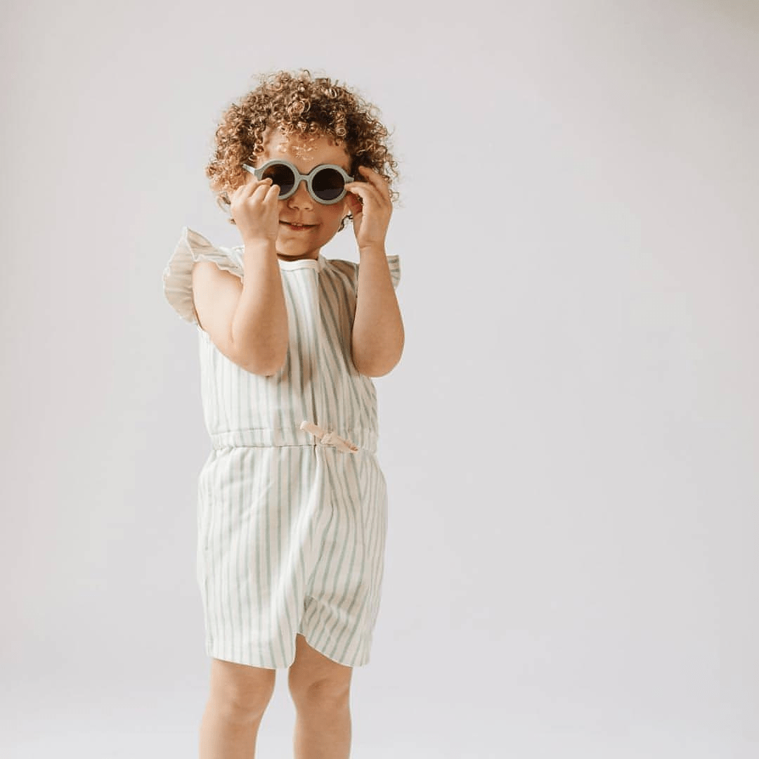 Little-Girl-Holding-Onto-Babiators-Euro-Round-Baby-Kids-Sunglasses-Into-the-Mist-Naked-Baby-Eco-Boutique