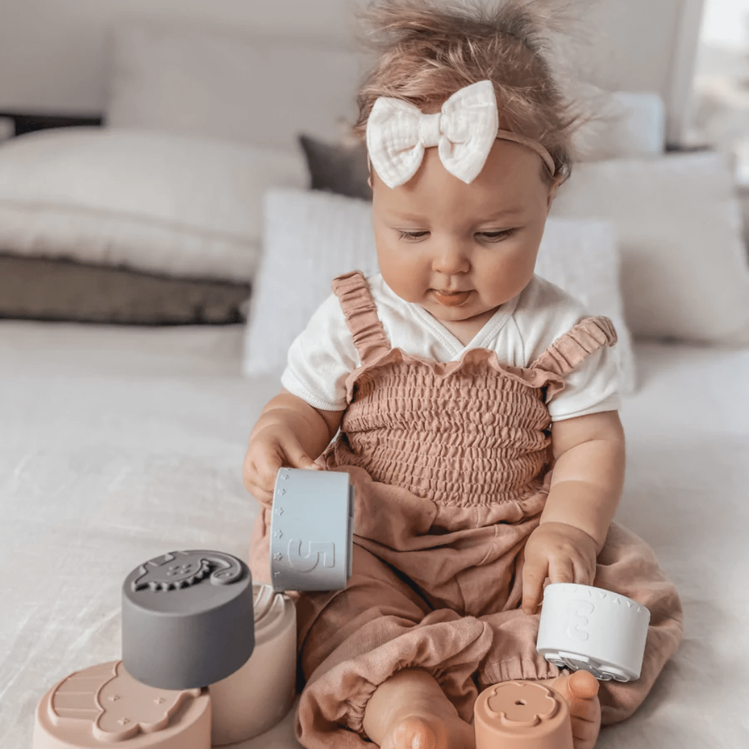 Little-Girl-Playing-With-Over-The-Dandelions-Stacking-Cups-Naked-Baby-Eco-Boutique