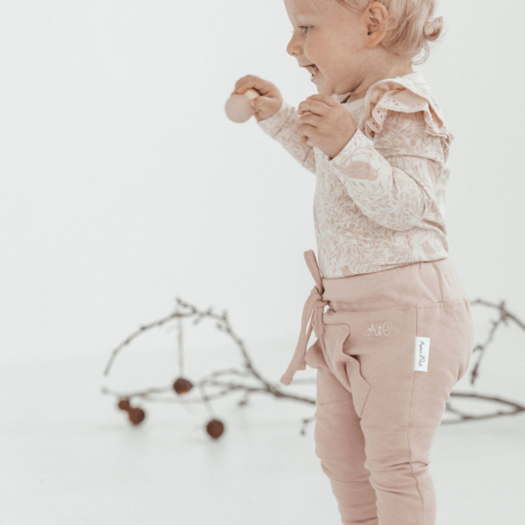 Little-Girl-Showing-Side-View-Of-Aster-And-Oak-Organic-Cotton-Jogger-Pants-Rose-Naked-Baby-Eco-Boutique