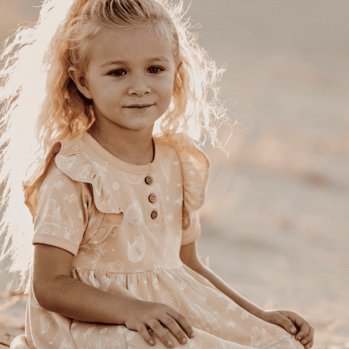 Little-Girl-Sitting-Down-Wearing-Aster-and-Oak-Organic-Mermaid-Skater-Dress-Naked-Baby-Eco-Boutique