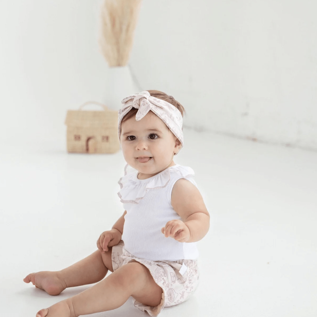 Little-Girl-Sitting-Wearing-Aster-and-Oak-Organic-Ruffle-Bloomers-Fairy-Garden-Naked-Baby-Eco-Boutique