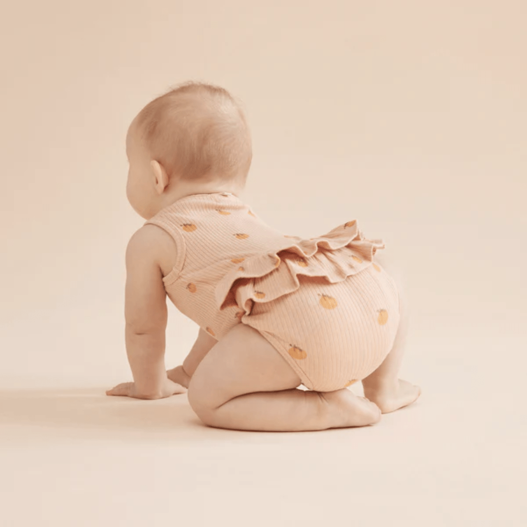 Little-Girl-Wearing-Wilson-And-Frenchy-Organic-Rib-Ruffle-Onesie-Little-Orange-Naked-Baby-Eco-Boutique