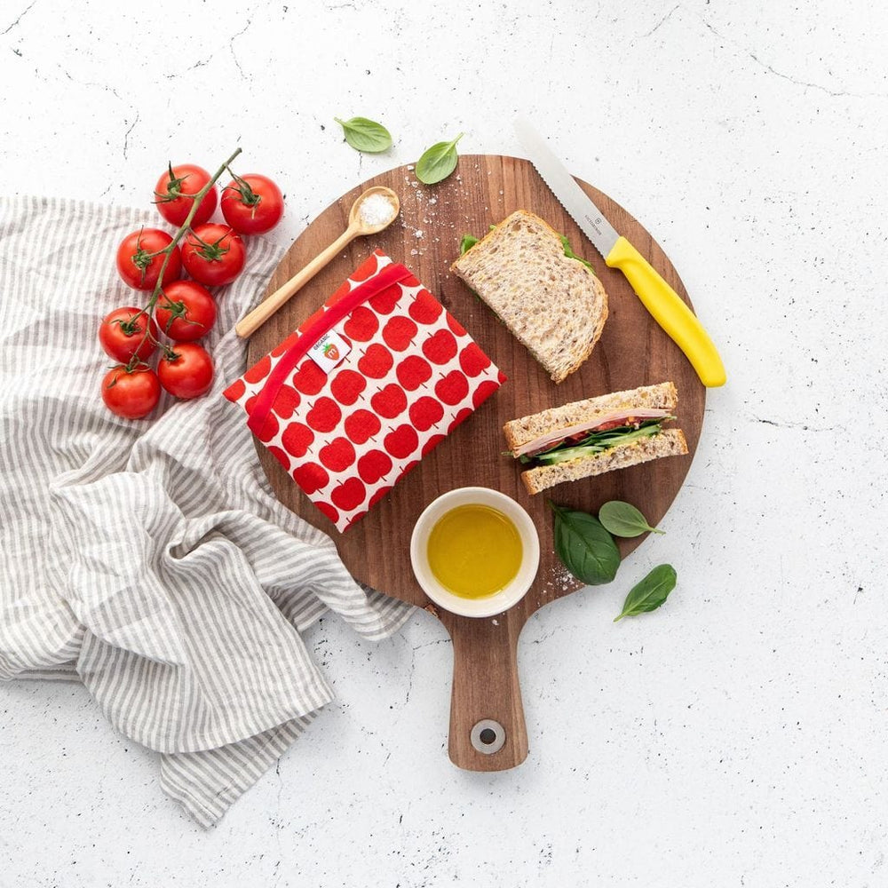 A Munch Organic Reusable Lunch Wrap - LUCKY LAST - GREEN APPLE on a cutting board with organic tomatoes and bread.