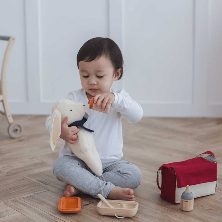 Plan-Toys-Doll-Feeding-Set-Little-Boy-Giving-His-Toy-A-Bottle-Naked-Baby-Eco-Boutique