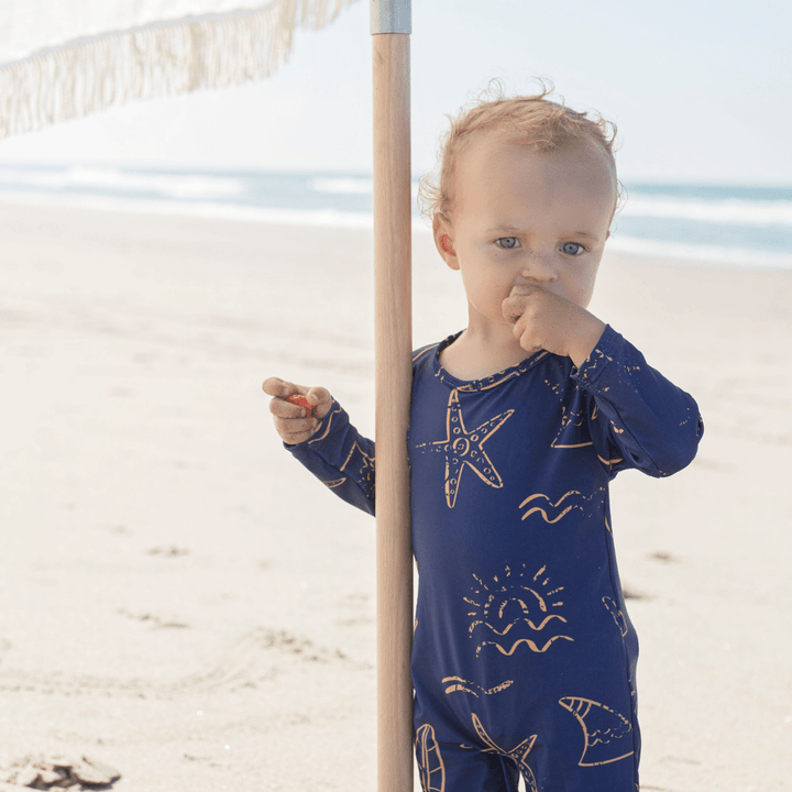 Little-Boy-Wearing-Saylor-Mae-Long-Sleeve-Swimsuit-Avery-at-Beach-Naked-Baby-Eco-Boutique