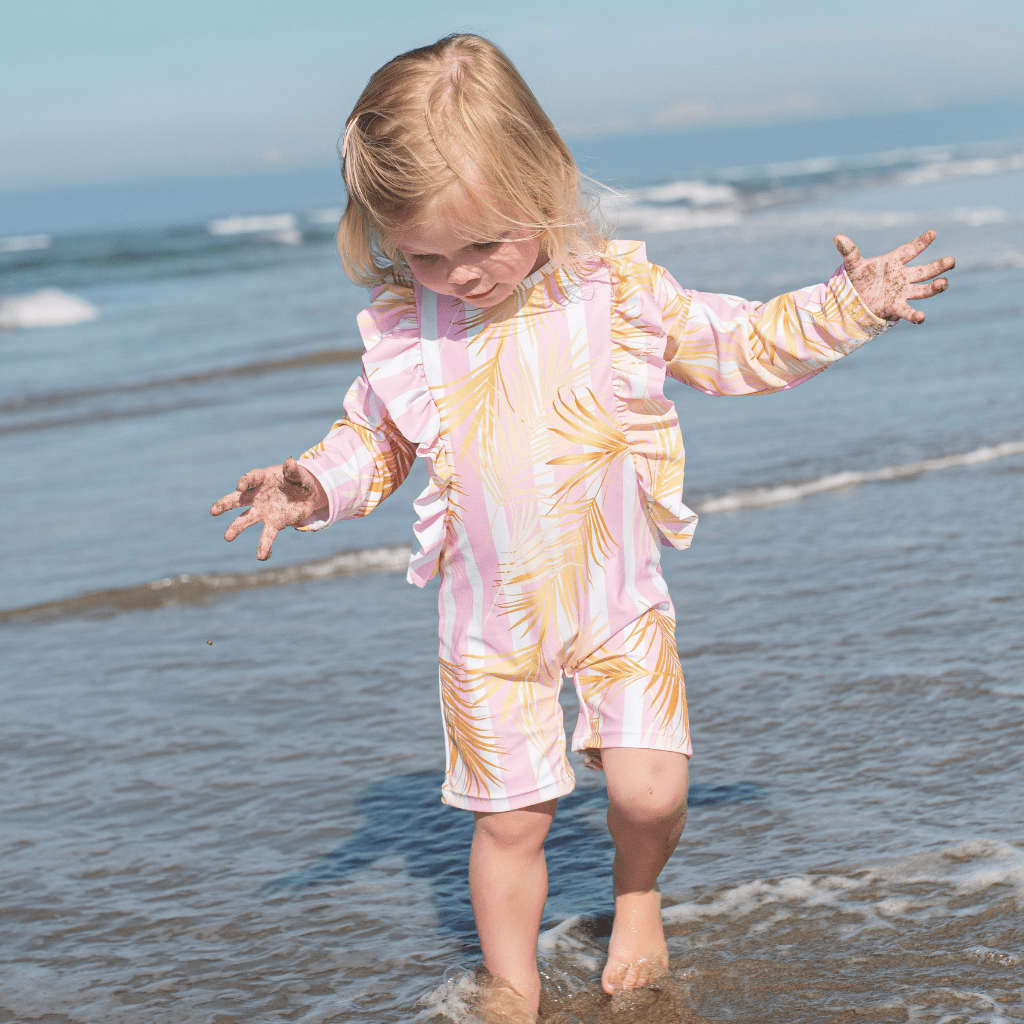 Little-Girl-Wearing-Saylor-Mae-Long-Sleeve-Swimsuit-Callie-at-Beach-Naked-Baby-Eco-Boutique