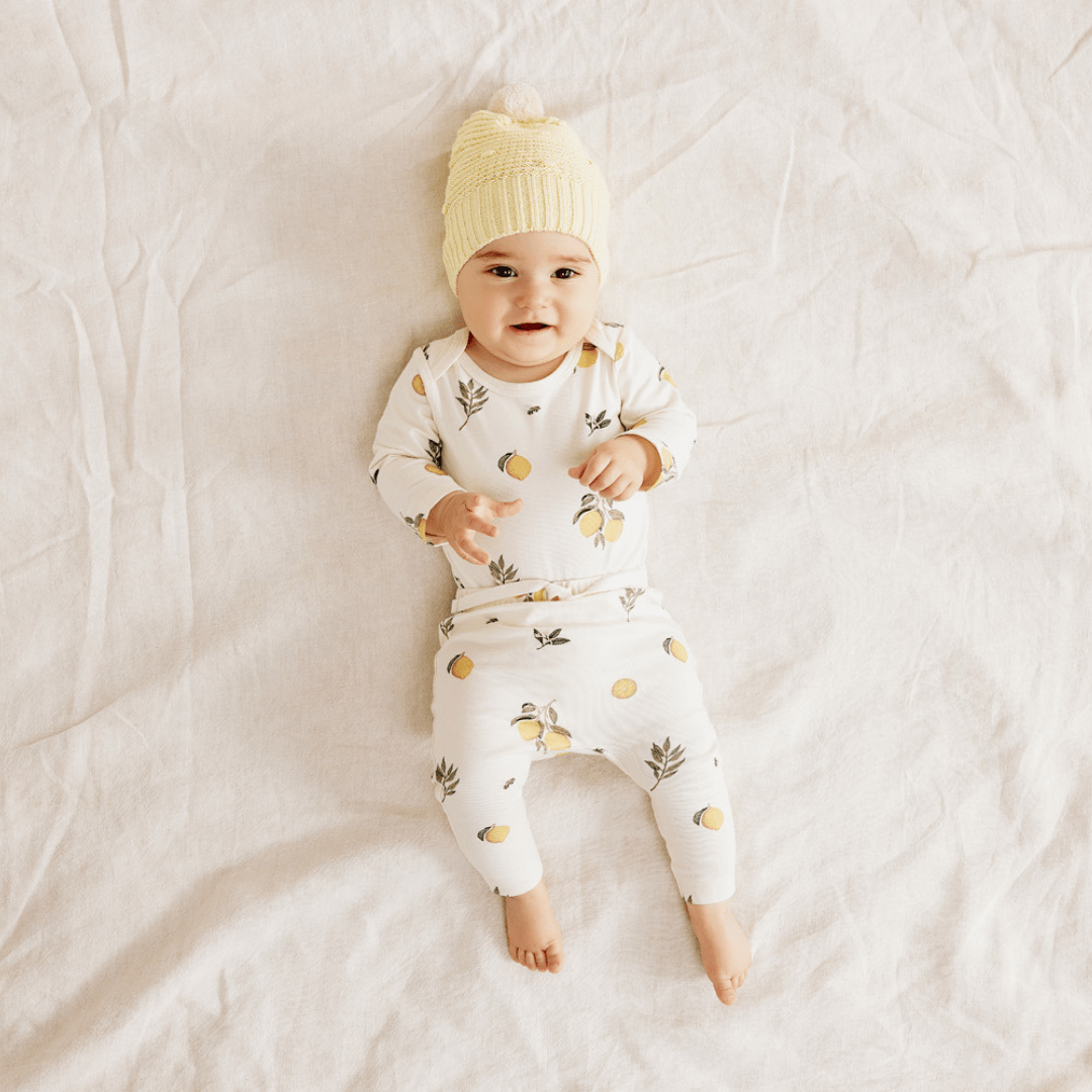 Smiling-Baby-Lying-Down-Wearing-Wilson-and-Frenchy-Organic-Cotton-Envelope-Onesie-Lovely-Lemons-Naked-Baby-Eco-Boutique