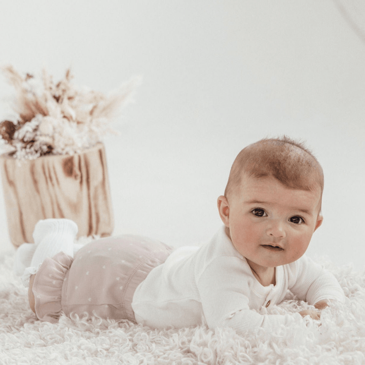 Smiling-Baby-on-Tummy-Wearing-Aster-and-Oak-Organic-Rib-Onesie-Snow-Naked-Baby-Eco-Boutique